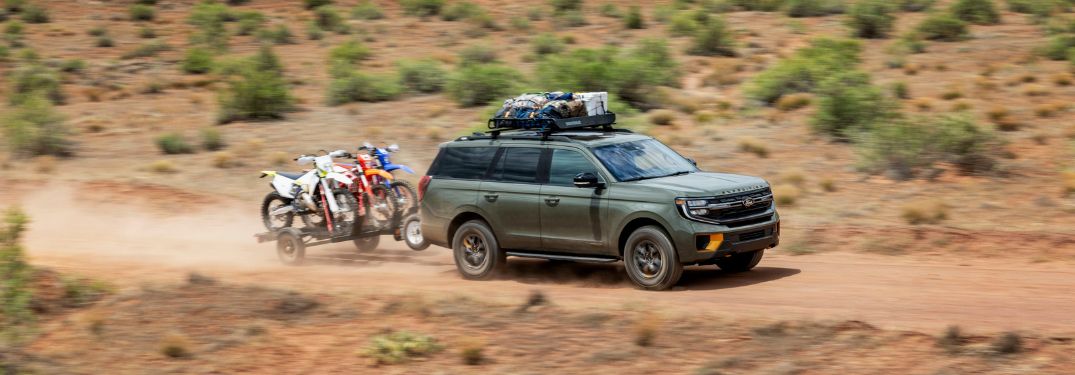 Green 2025 Ford Expedition Towing Dirt Bikes in a Desert