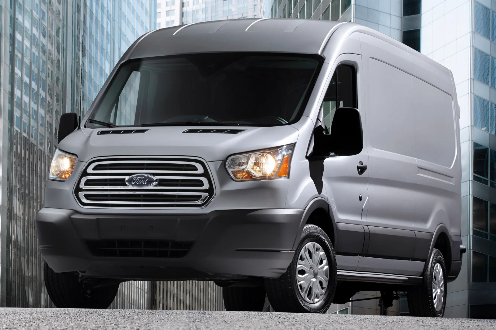 a gray Ford Transit 250 in a city street with skyscrapers around it