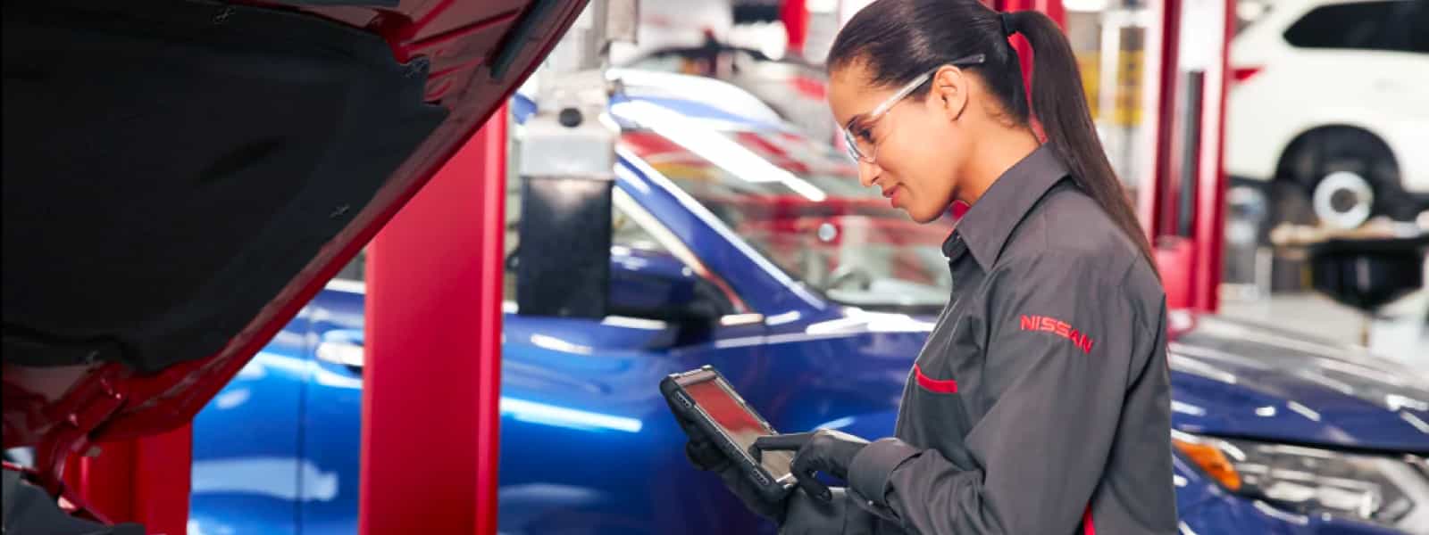 Nissan technician servicing a vehicle on a lift in the United Nissan service department