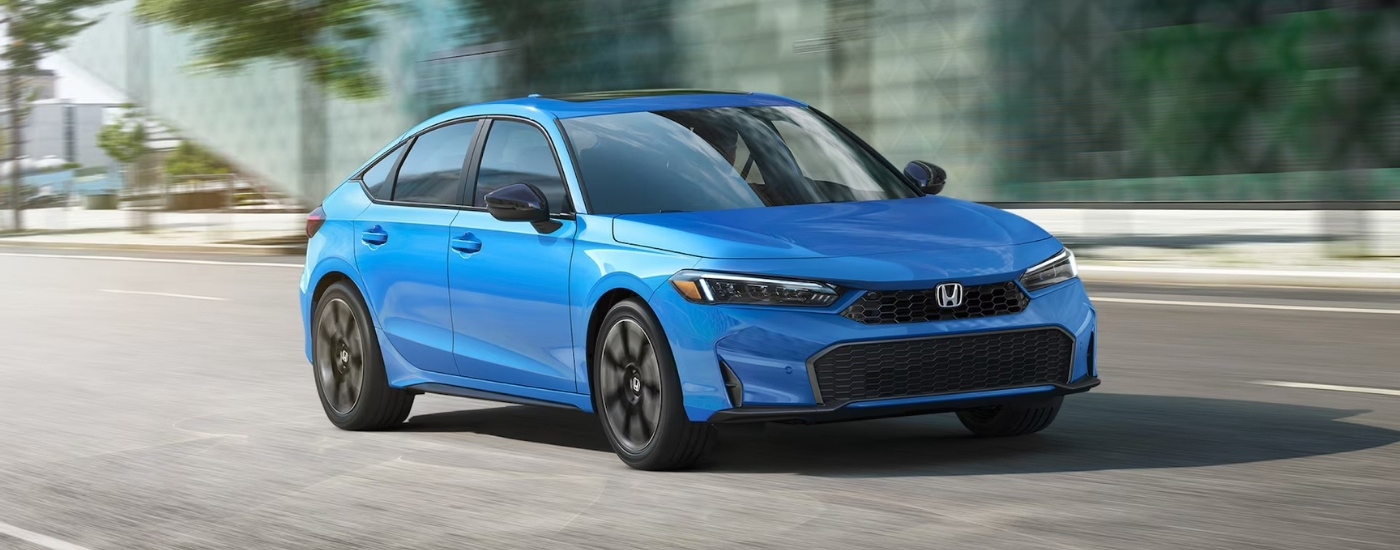 Blue 2025 Honda Civic Hatchback Sport Touring driving on a city street