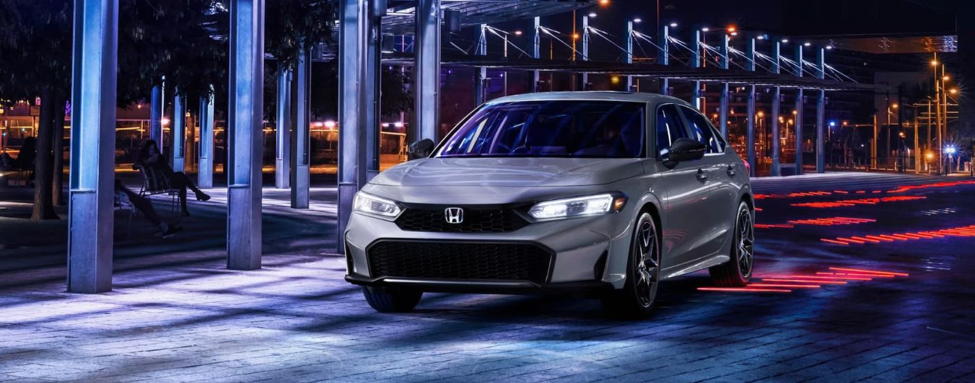 Grey 2025 Honda Civic driving through a city at night