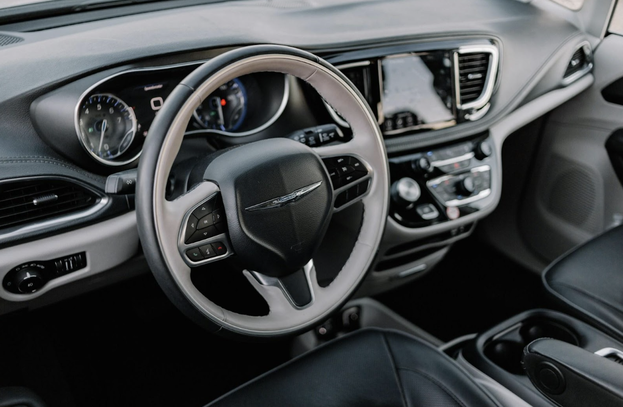 Interior shot of a car's dashboard and steering wheel with the Chrysler logo and a digital display.