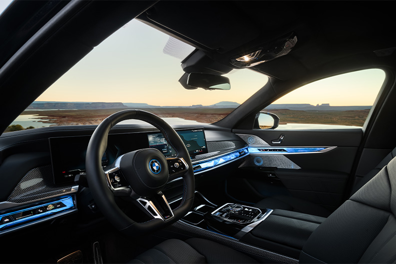 Dashboard view of a 2026 BMW i7 M70 parked in flat, desert landscape with the sun setting in the background. 