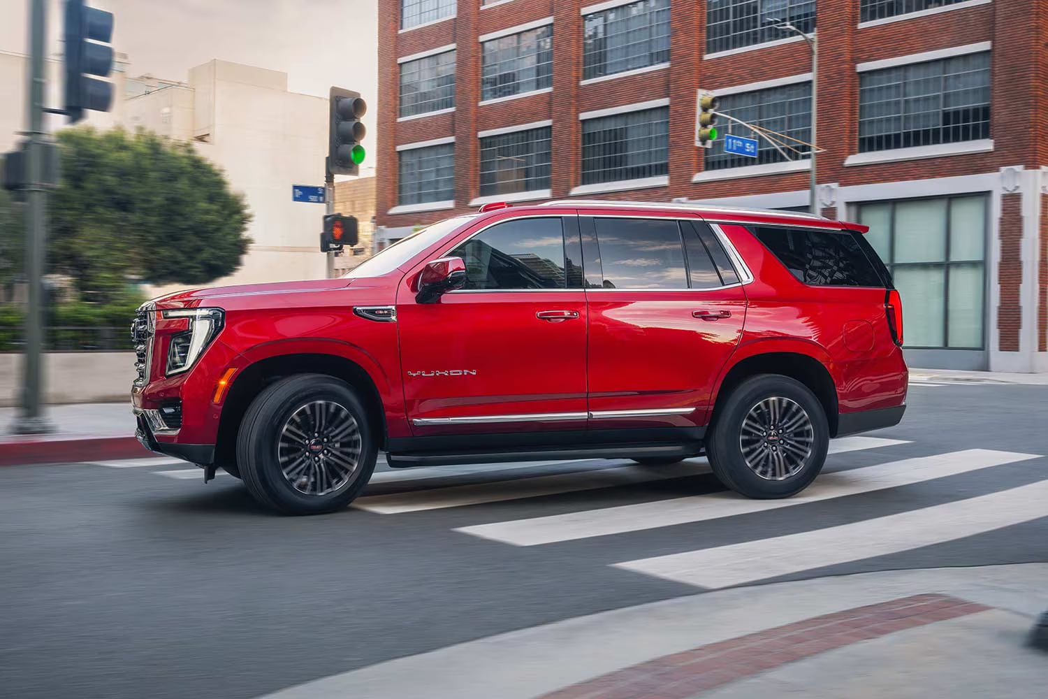 Red GMC Yukon driving through a city intersection