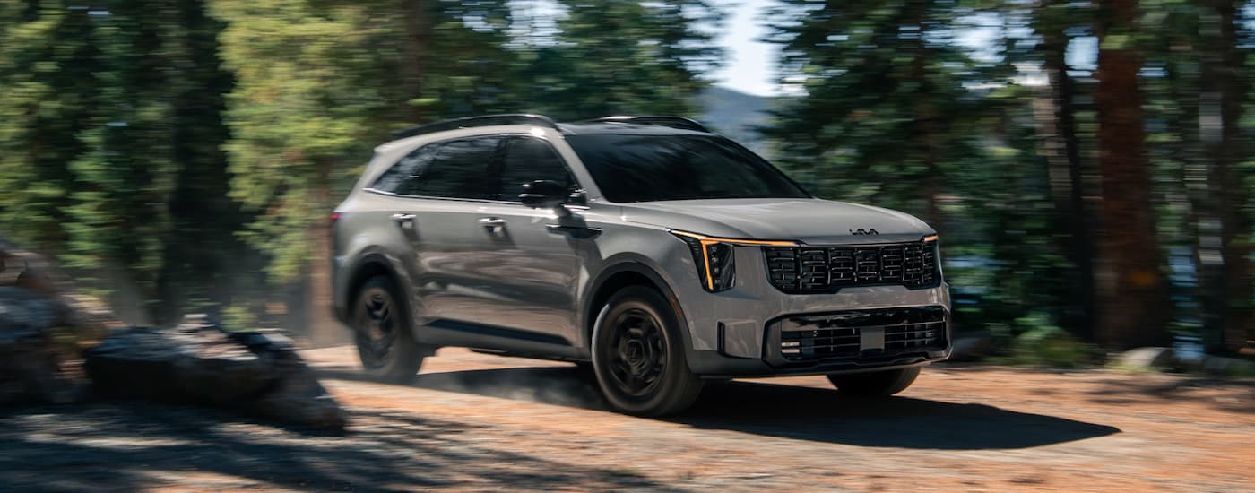Grey 2026 Kia Sportage X-Pro SX Prestige driving off-road on a dirt trail.
