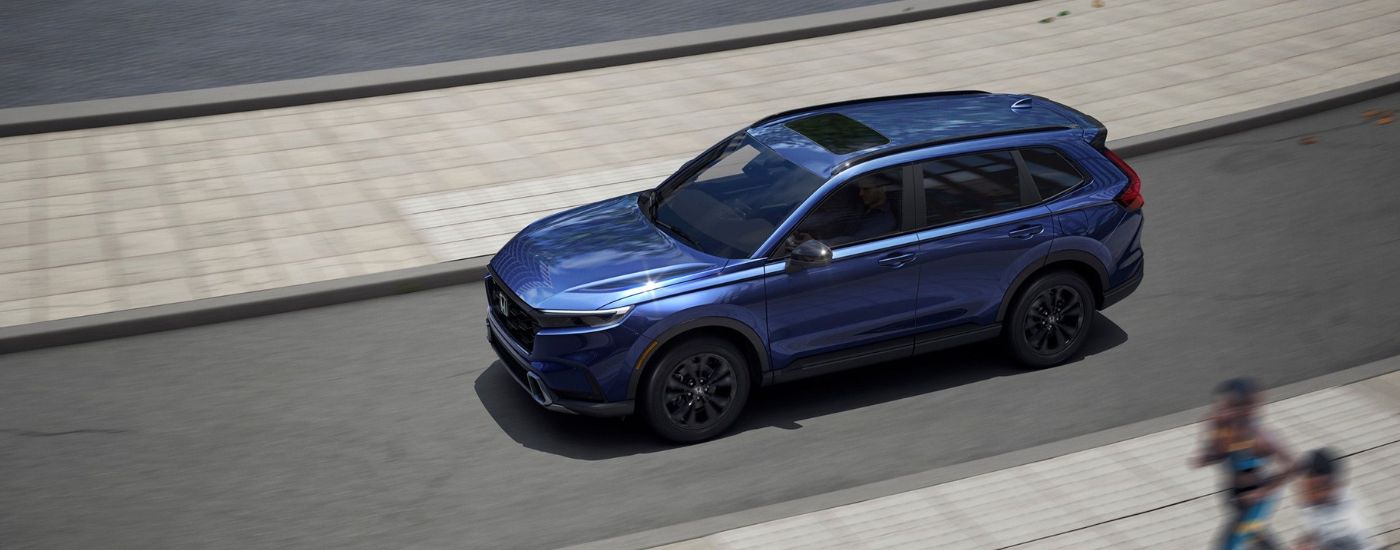 Aerial view of a blue 2026 Honda CR-V driving on a paved road.