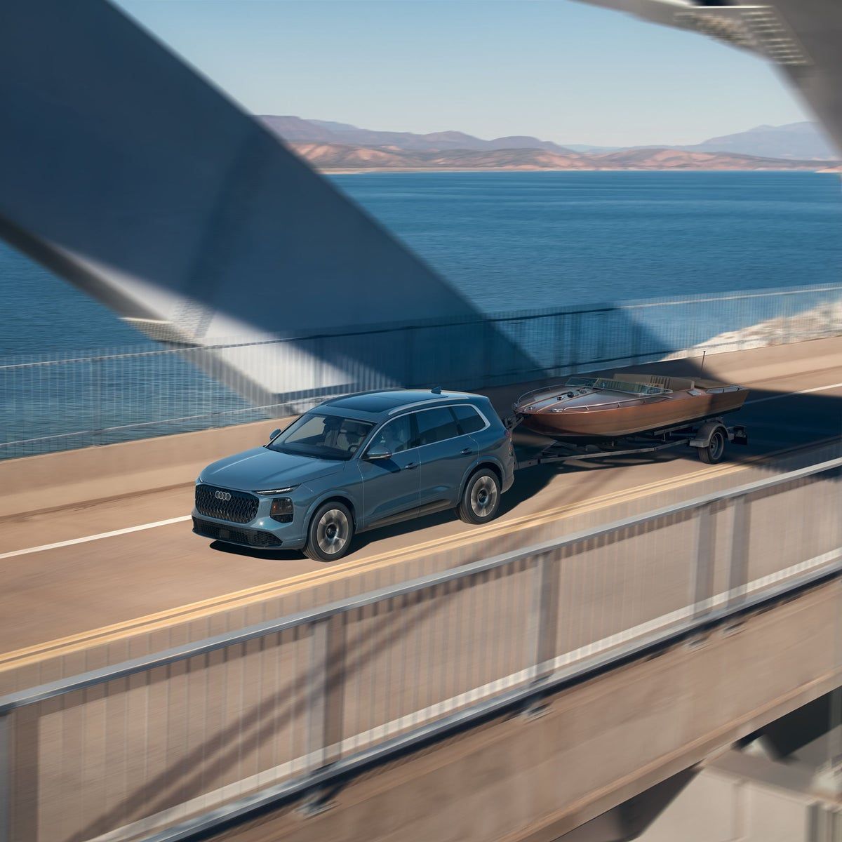 2027 Audi Q7 towing a boat trailer across a bridge, 7,700 pound maximum tow rating