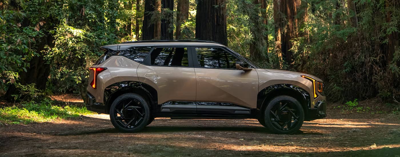 Side of a brown 2027 Kia Seltos parked off-road in a forest.