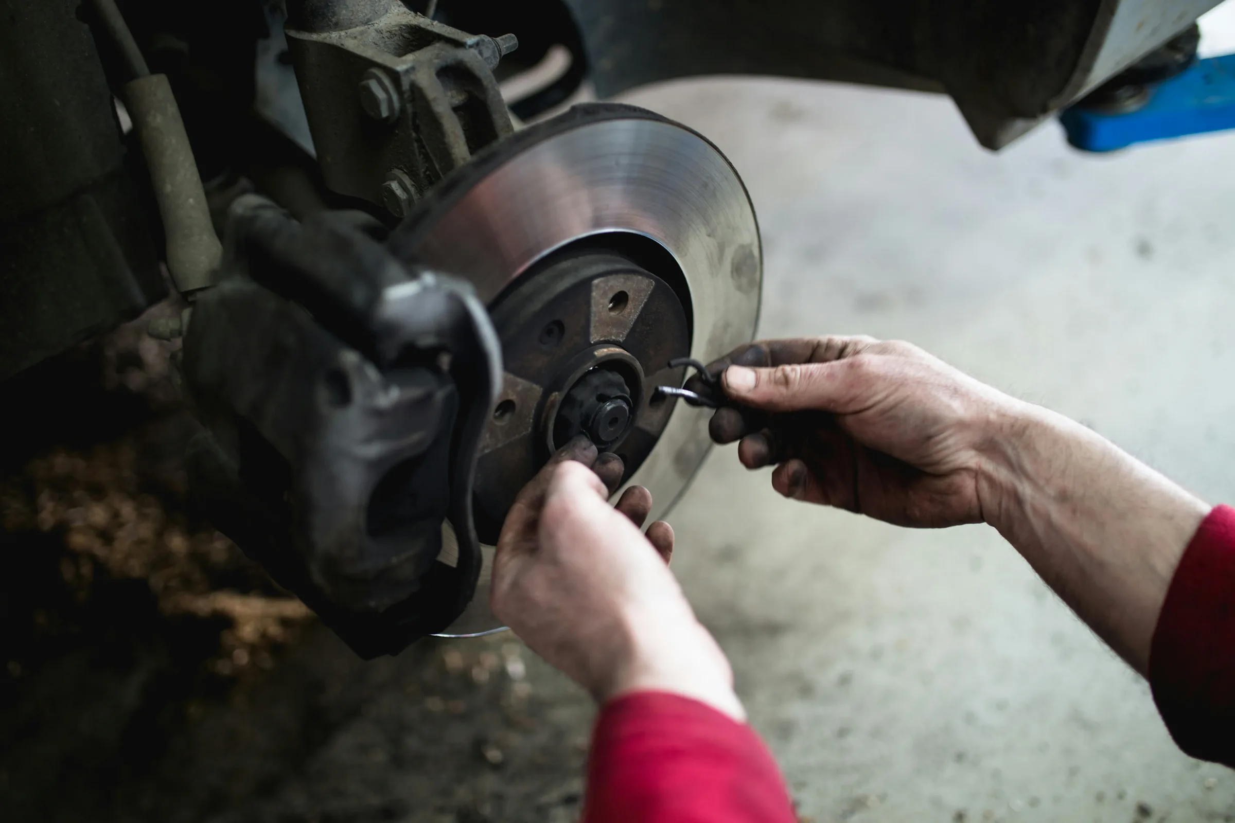 Technician's hands attaching a retaining clip to a brake rotor during a brake service. Brake Pads Service Near Leavenworth, KS