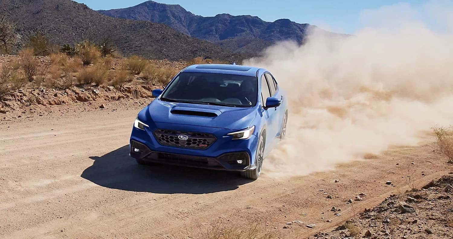 Blue Subaru WRX kicking up dust on a dirt road