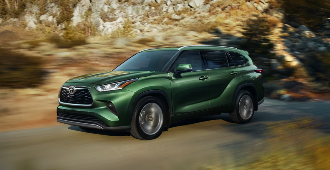 2024 Toyota Highlander in green paint color driving through mountain roads.