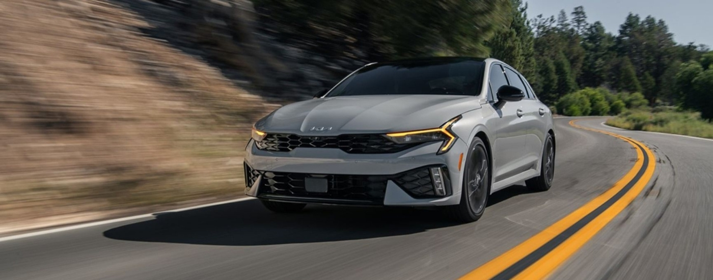Grey 2025 Kia K5 driving to a Kia dealer near Minneapolis