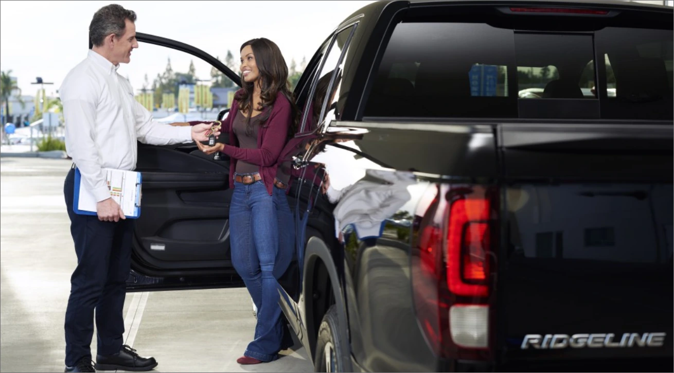 Allen Honda team member handing keys to a customer beside a Honda Ridgeline
