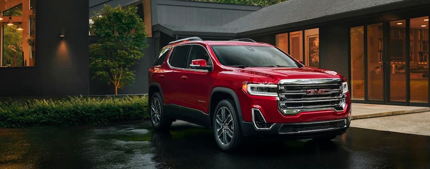A red 2023 GMC Acadia Denali is shown from the front at an angle.