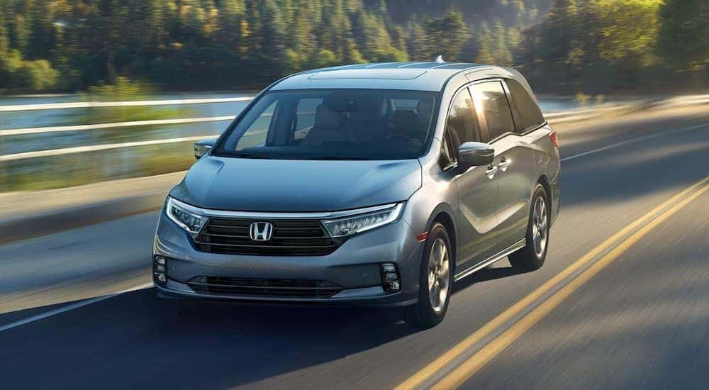 A silver 2024 Honda Odyssey is shown from the front at an angle after leaving a dealer that has a Honda Odyssey for sale.