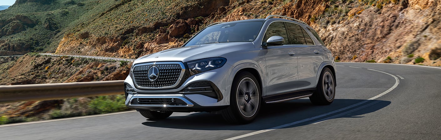 2027 Mercedes-Benz GLE SUV in silver driving along a winding desert mountain road