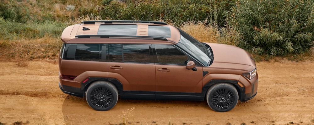 Side profile of a bronze 2026 Hyundai Santa Fe on a dirt trail