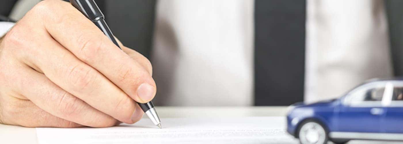 man signing document at car dealership