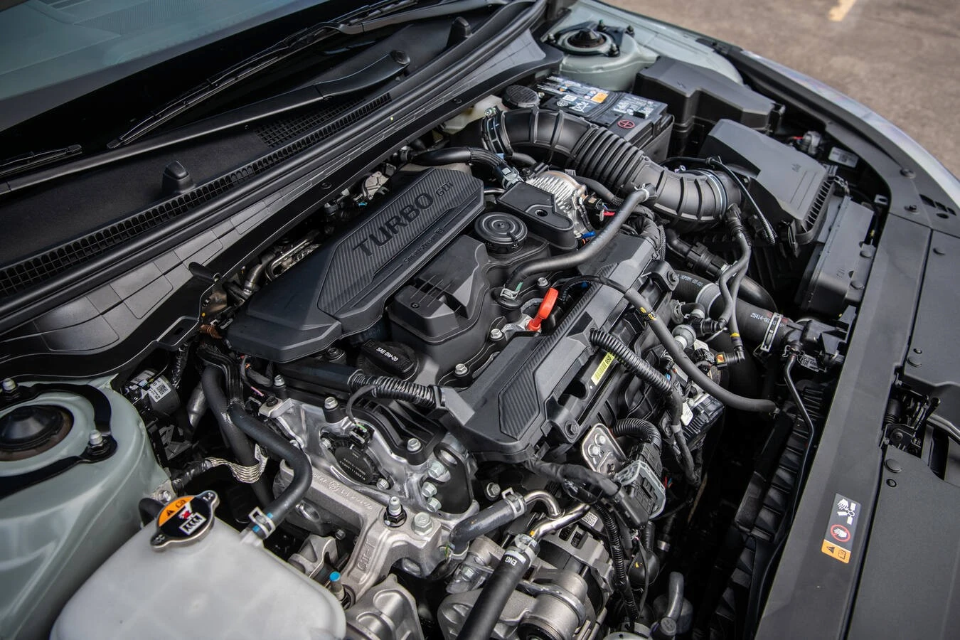 Turbo GDI engine bay of a 2026 Kia K4, viewed from above with the hood open
