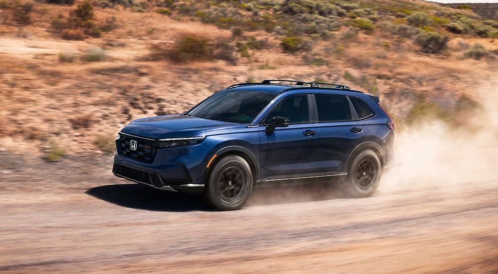 Blue 2026 Honda CR-V driving on a dirt road trail