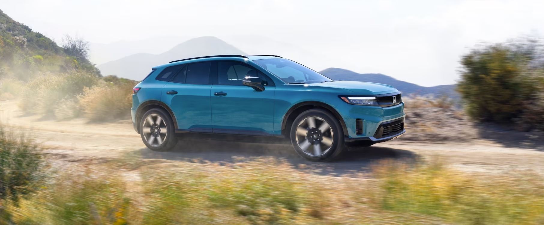 blue 2024 Honda Prologue EV driving on a gravel dirt road