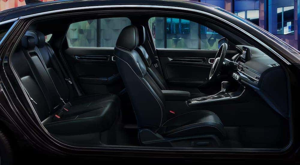 The front and back seats in the black interior of a 2024 Honda Civic Hatchback.