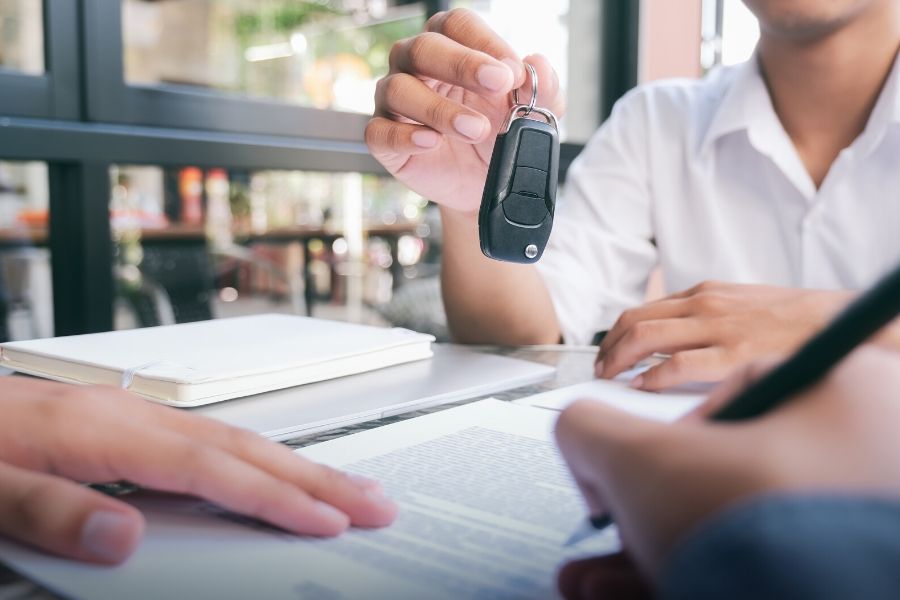 Person holding keys while other person signs papers