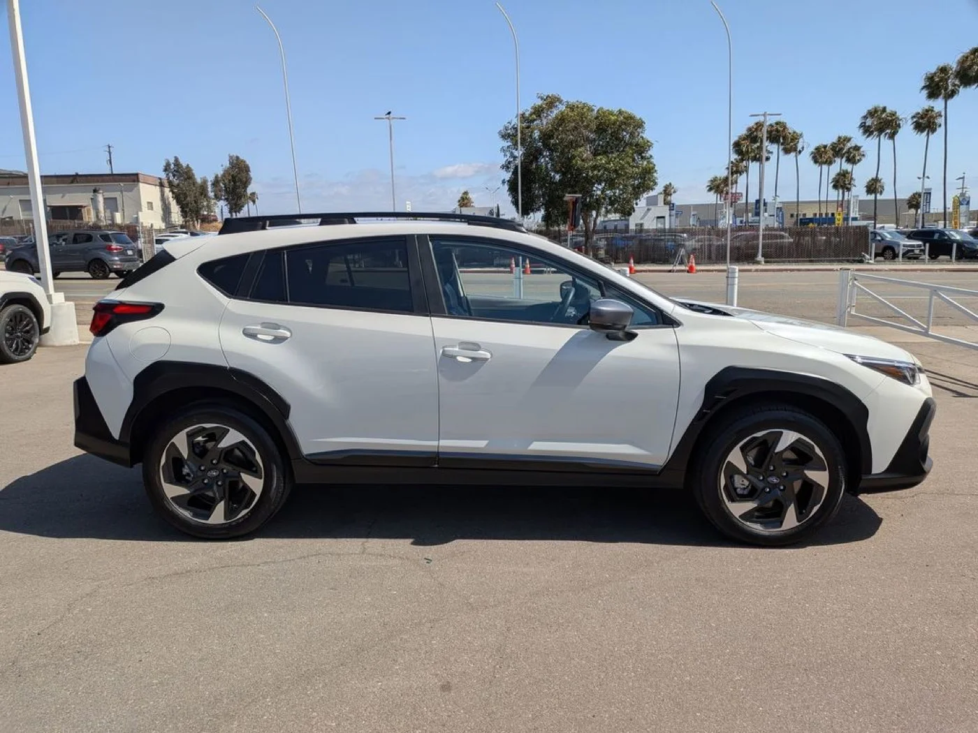 Side profile of the white used 2024 Subaru Crosstrek Premium showing alloy wheels and roof rails, at Dalton Subaru National City