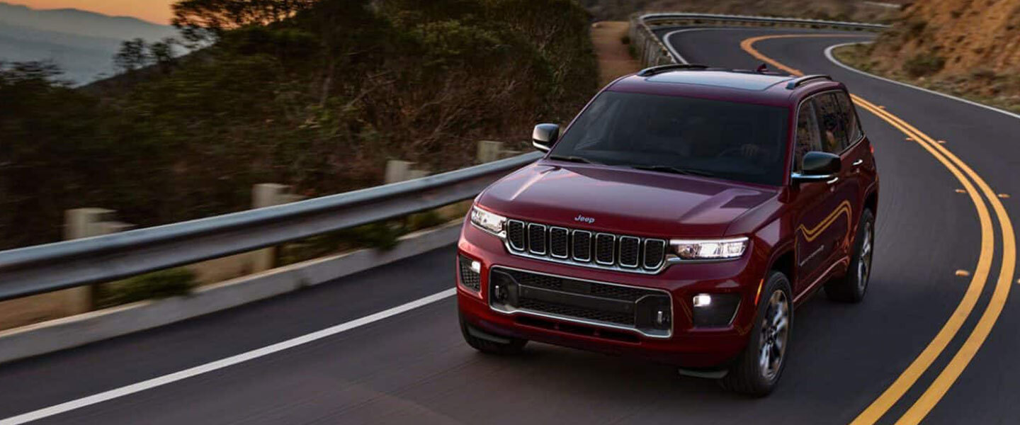 A red 2022 Jeep Grand Cherokee driving.