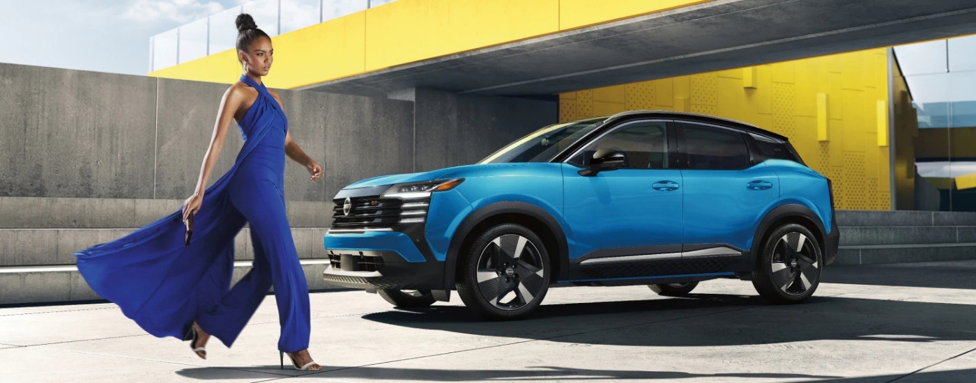 Person walking past a blue 2026 Nissan Kicks SR