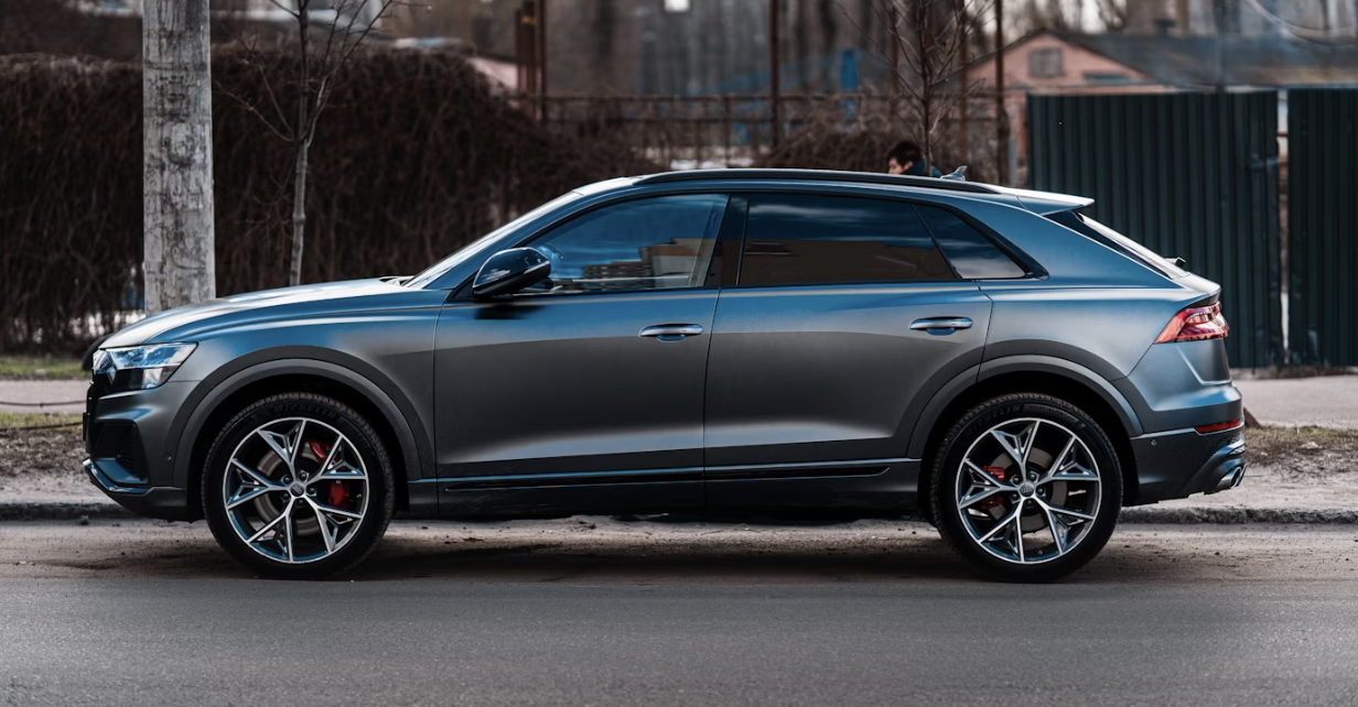 Side profile of a dark grey SUV parked on an urban street.