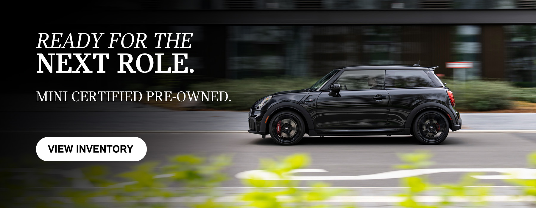 Side view of black MINI 2 Door driving down the road