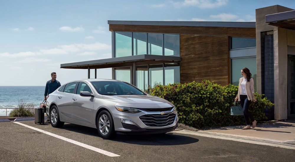 A couple getting into their silver 2024 Chevy Malibu.