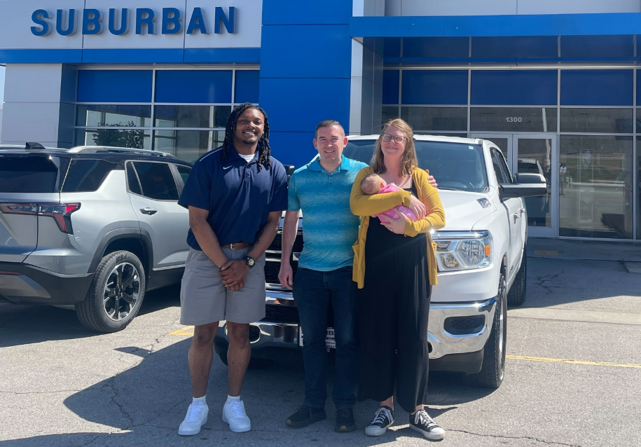 young family smiling in front of a new chevrolet silverado 1500 in white with the sales agent who sold them the truck near Bixby, OK