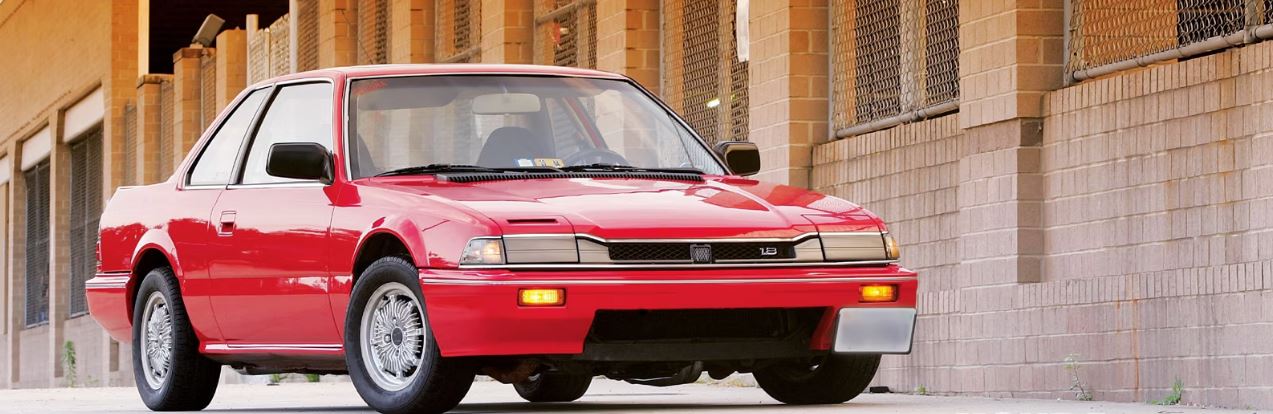 1985 red Honda Prelude parked next to a state prison