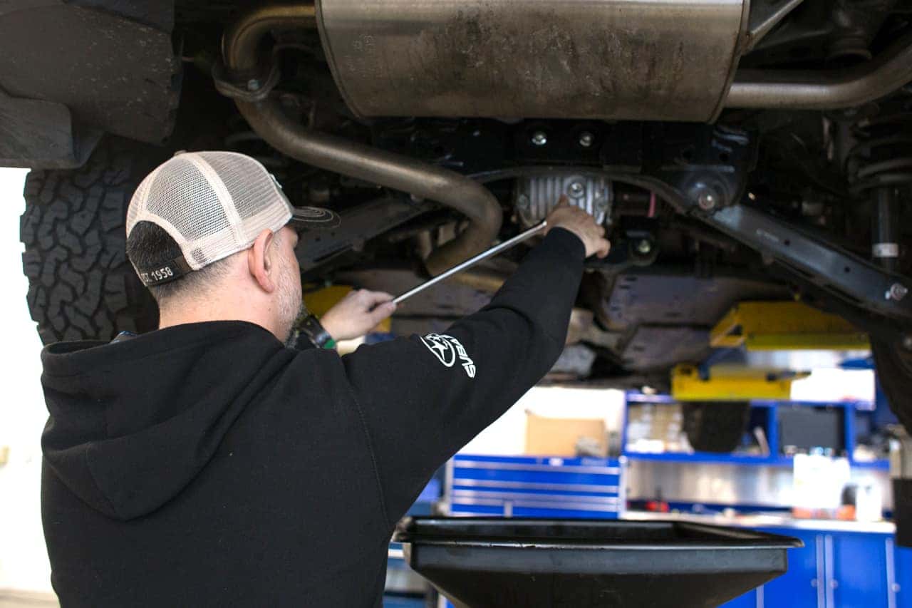 Subaru technician working underneath a vehicle on a lift