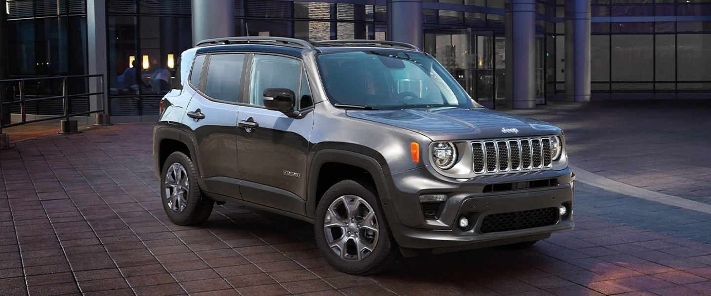 A gray jeep sitting parked parked in front of a building.