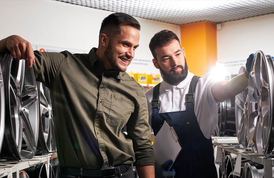 Técnico y cliente revisando rines en el taller de servicio