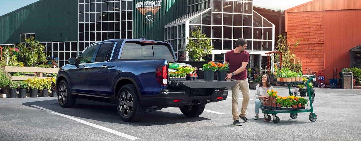A couple is loading plants into the bed of a blue 2020 Honda Ridgeline RTL-E in front of a garden center near Rochester, NY.