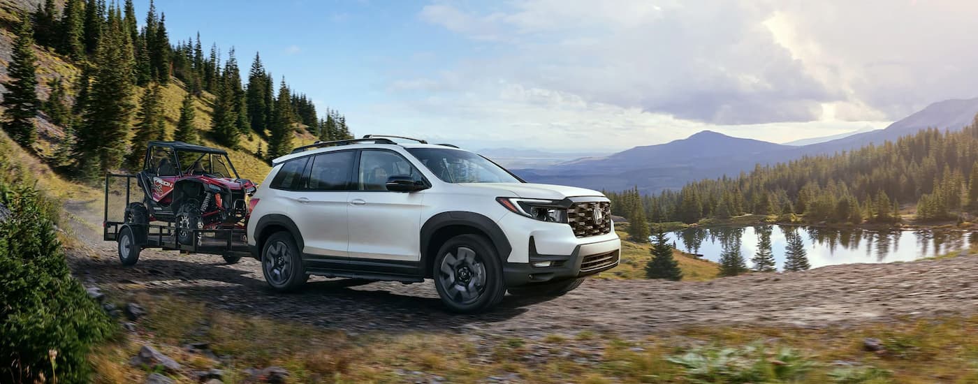 White 2022 Honda Passport Elite off-roading near a lake
