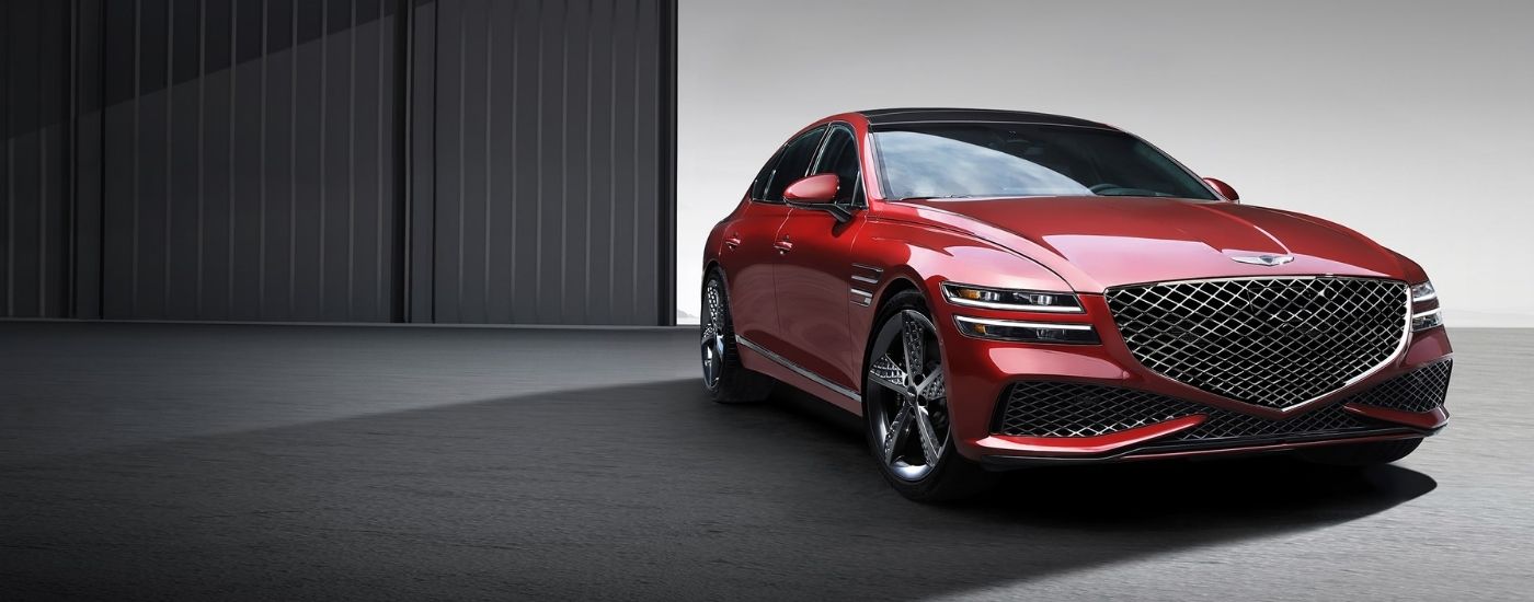 Red 2023 Genesis G80 parked in front of a garage