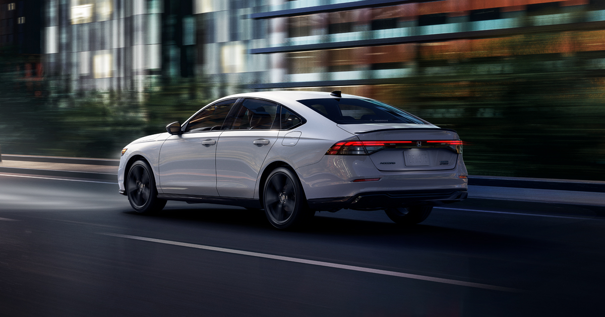 A white Honda Accord Hybrid driving through city streets.