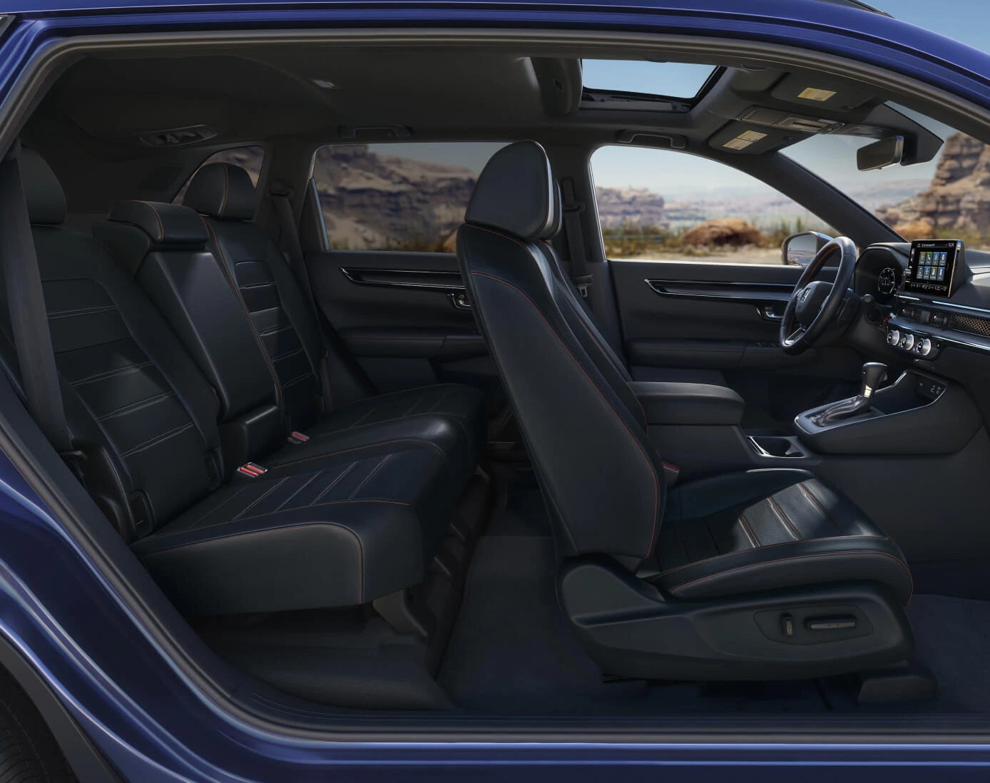 Side interior view of a Honda CR-V in black leather with orange stitching facing a desert backdrop.