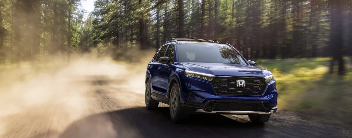 A blue 2026 Honda CR-V driving on a dirt road