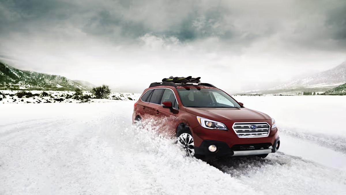 Red Subaru Outback driving through deep snow