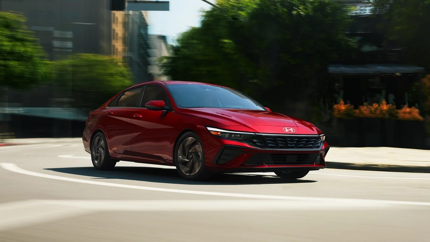 Red 2024 Hyundai Elantra driving through a city