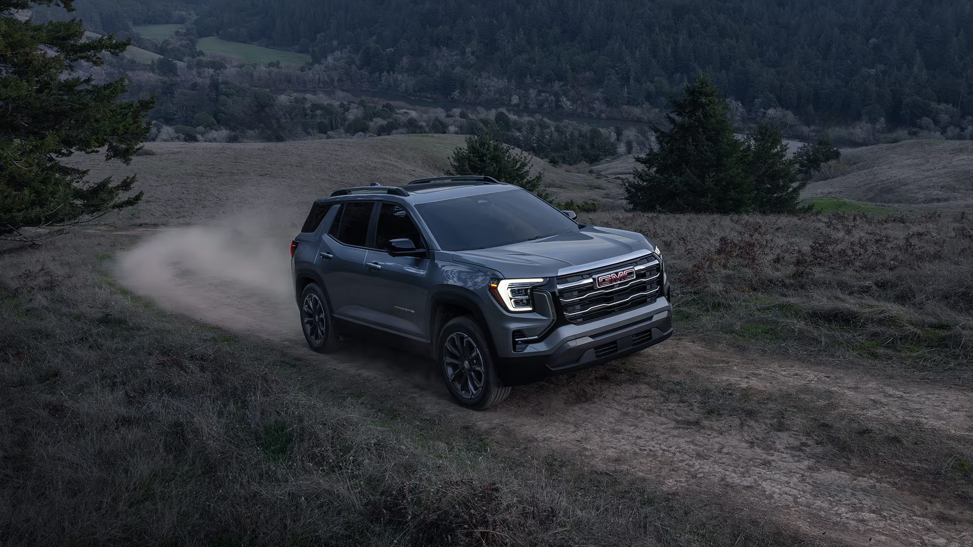 Gray GMC Terrain Elevation driving on a dirt trail through rolling hills